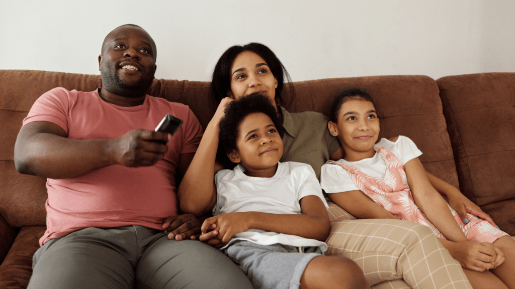 A family sitting on the couch watching TV