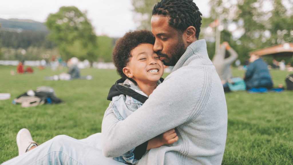 A father and son laying on the grass in a park