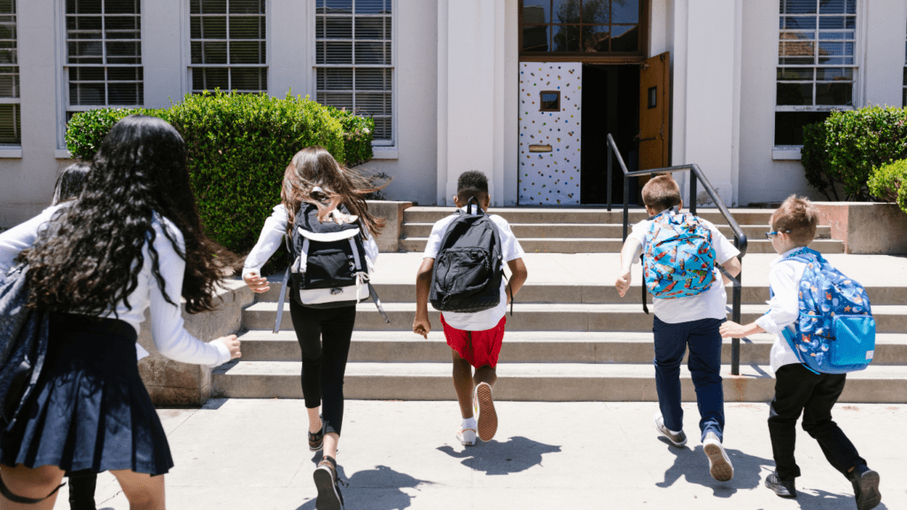 a group of children walking down the steps of a school