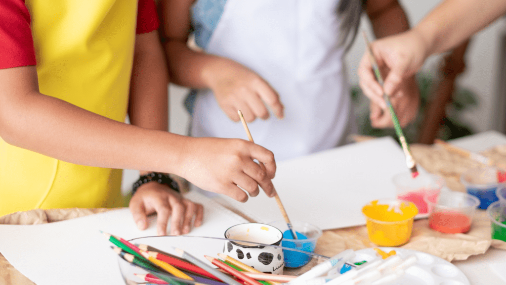 children painting with paint and brushes on a table