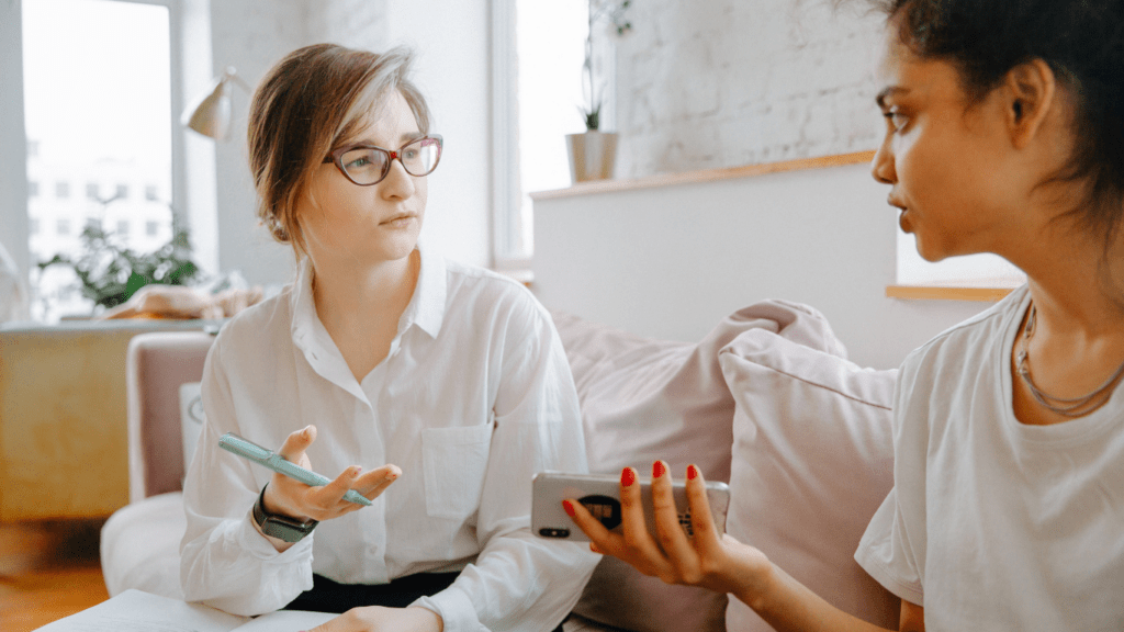 two people sitting on a couch talking to each other