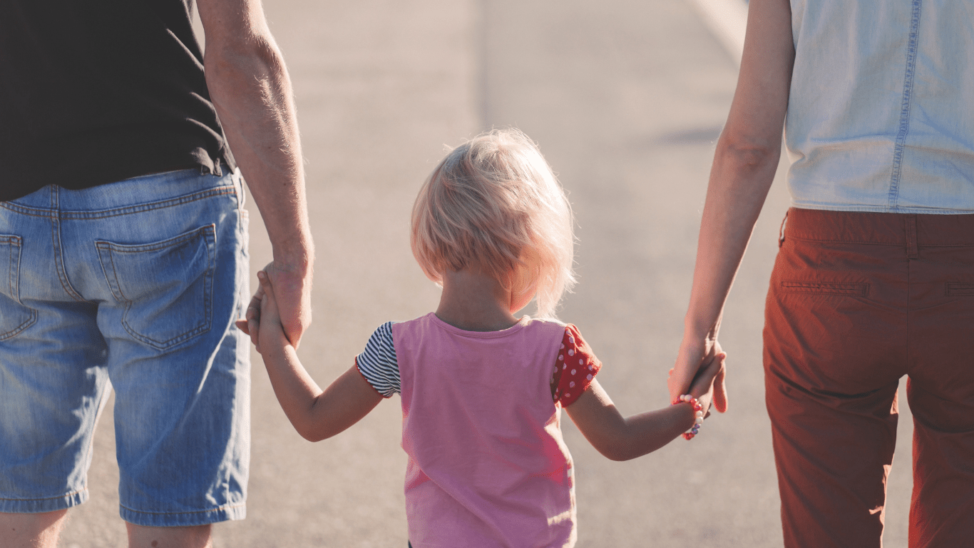 Two people holding hands with a child