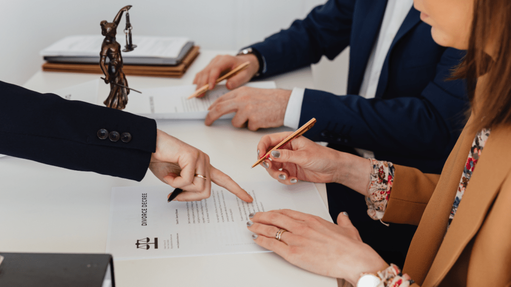 three people sitting at a table with papers and pens