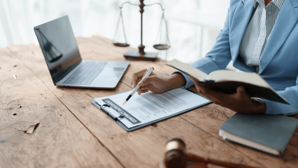 a person in a business suit sitting at a desk with a laptop and a gavel