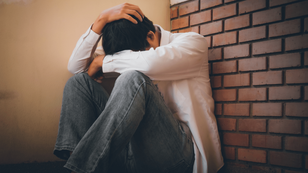 a person sitting on the floor with their head in their hands