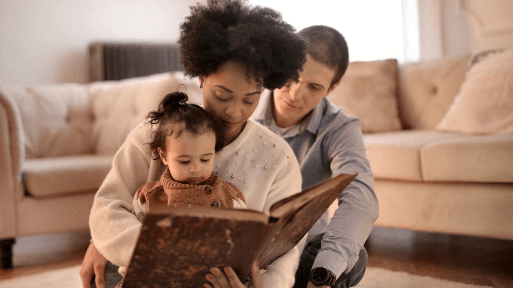 A family sitting on the floor reading a book