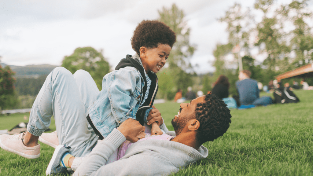 A father and son laying on the grass in a park