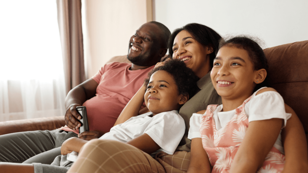 a family smiling and sitting on a couch in a living room