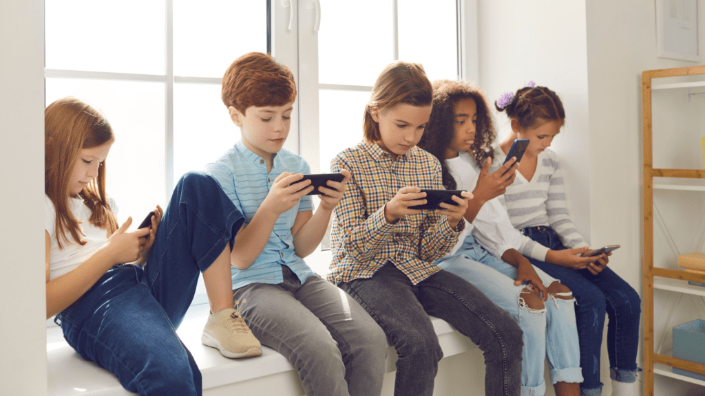 a group of children sitting on a couch with their cell phones