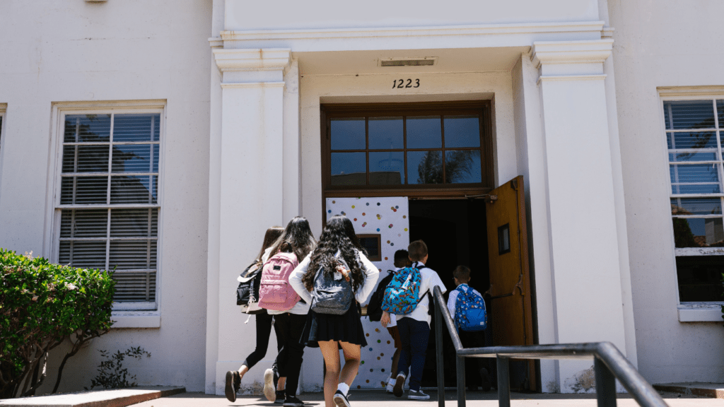 a group of children walking down the steps of a school