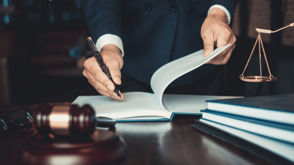 a person in a business suit sitting at a desk with a laptop and a gavel