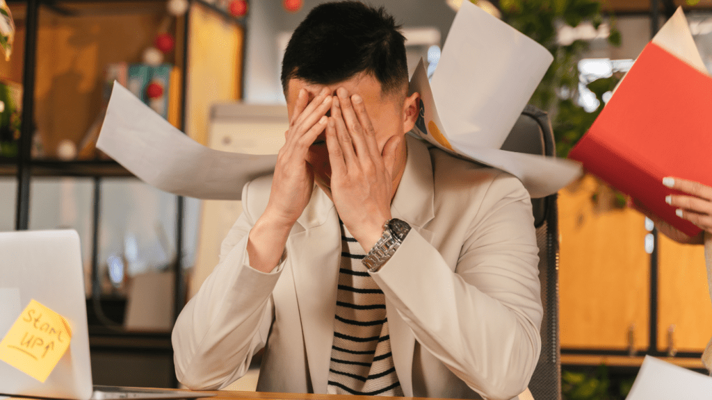 a person sitting at a desk with their head in their hands