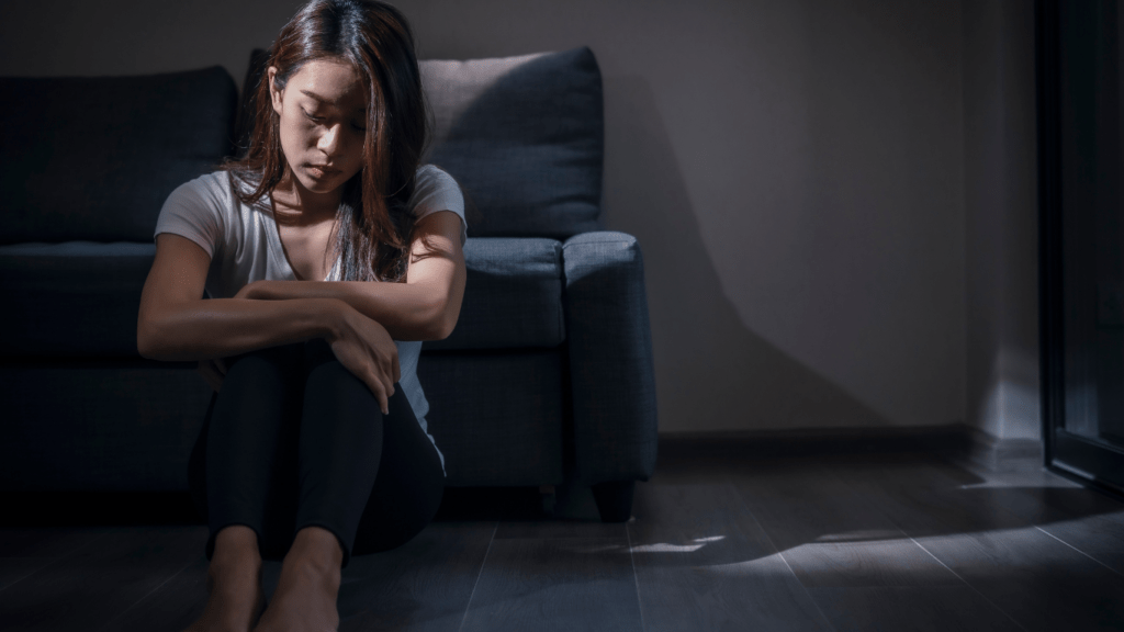 a person sitting on the floor with their head in their hands