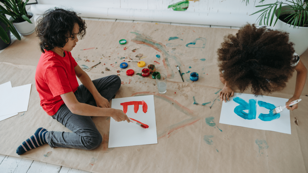 children painting with paint and brushes on a table