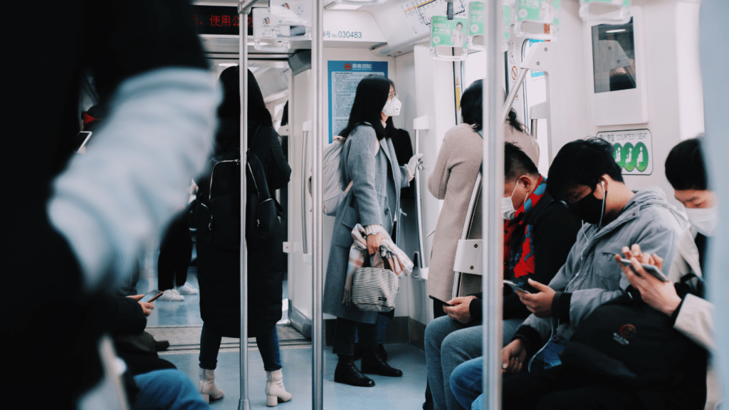 people wearing face masks walk through a subway station