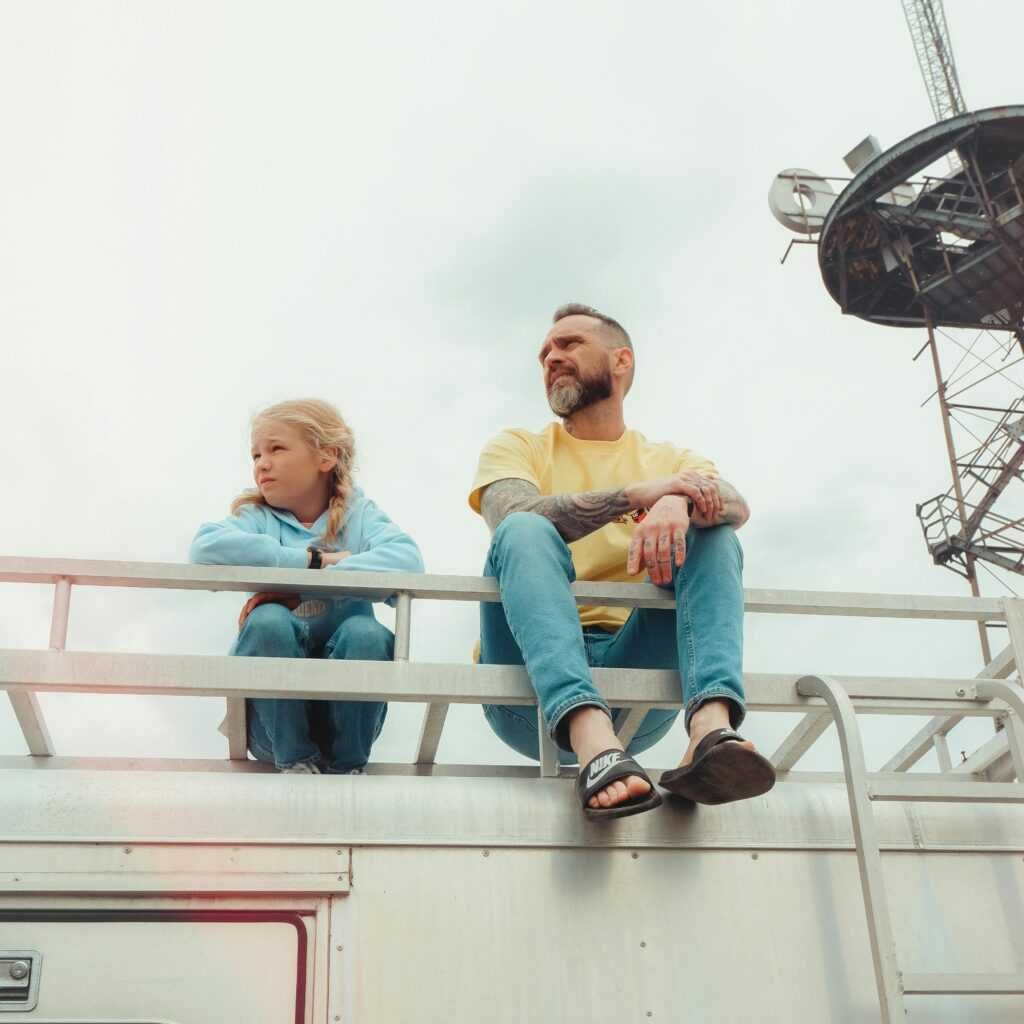 Woman in Blue Denim Jeans Sitting on White Metal Railings