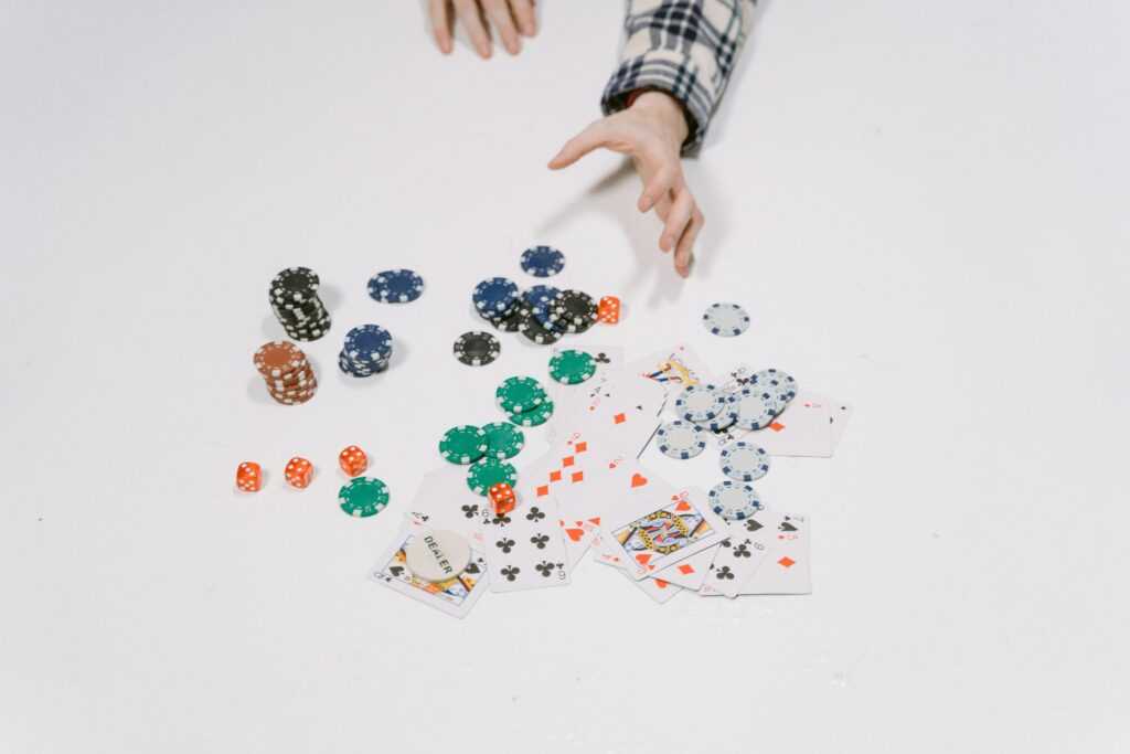 Close-up of poker chips and cards on a white surface, capturing a moment in a card game.