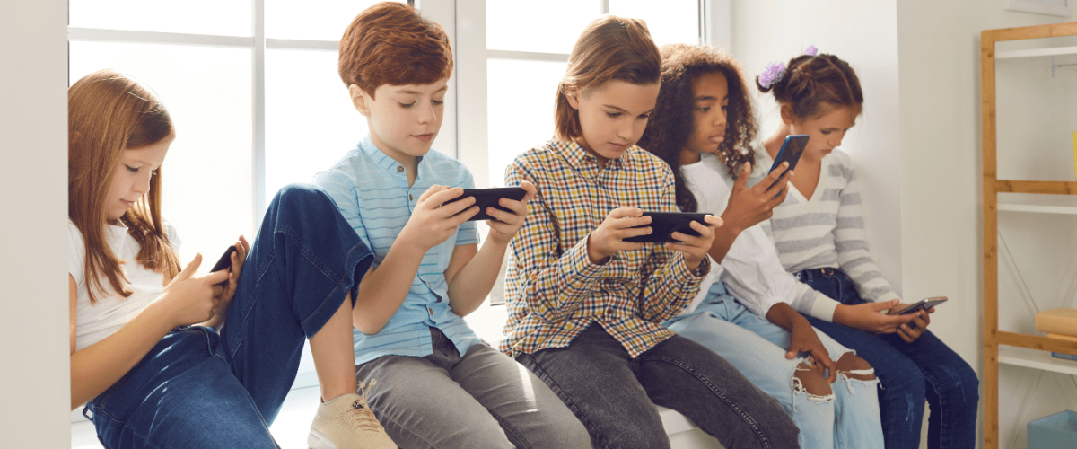 a group of children sitting on a couch with their cell phones